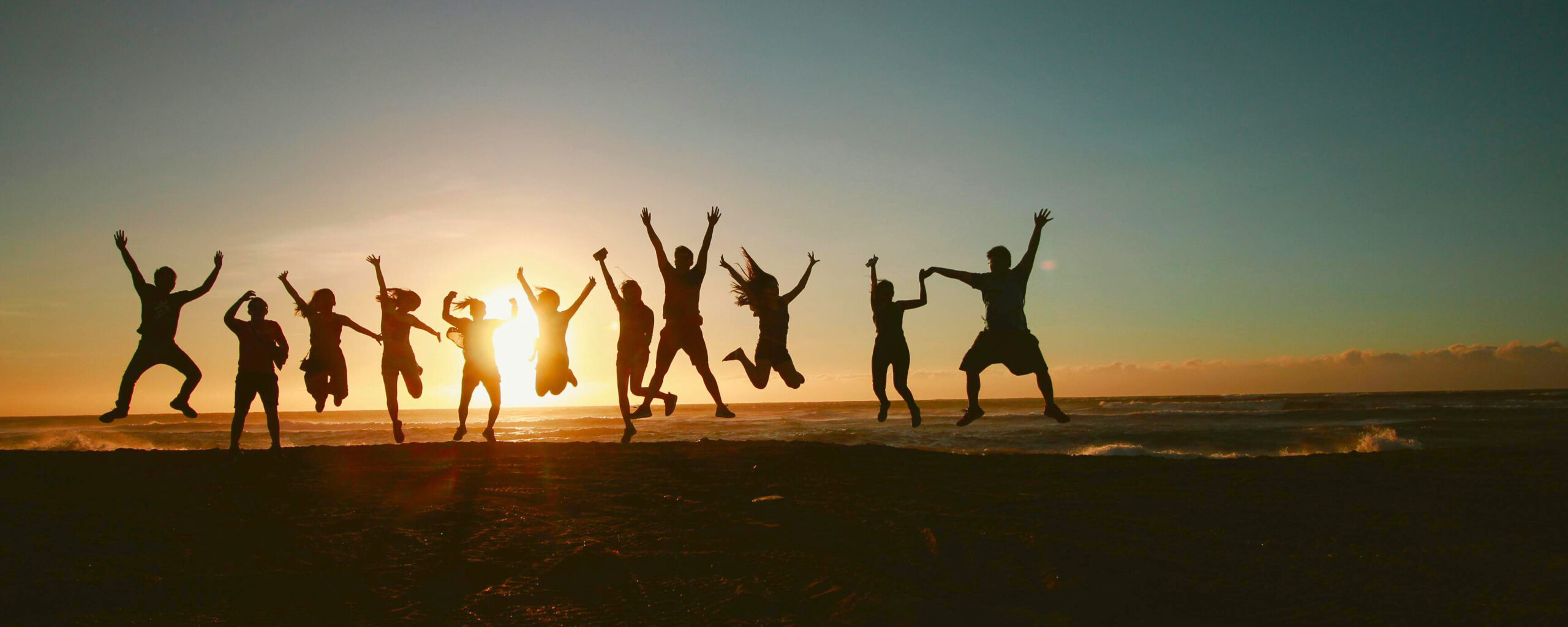 Happy remote team celebrating productivity on the beach at sunset
